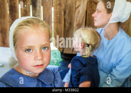 Amish girls in traditional blue dress and white hats overlooking the ...