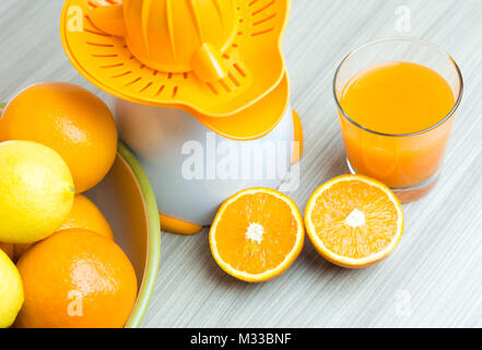 Glass of squeezed orange juice. Fresh and juicy oranges on the wooden table. Stock Photo