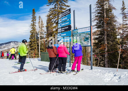 Colorfully dressed downhill skiers looking at the Trail Map of the Steamboat Ski Resort, Colorado;  on a nice winter day; two skiers are overweight Stock Photo