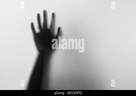 Shadow hands of the Man behind frosted glass.Blurry hand abstraction.Halloween background.Black and white picture Stock Photo