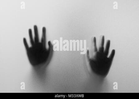 Shadow hands of the Man behind frosted glass.Blurry hand abstraction.Halloween background.Black and white picture Stock Photo