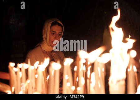 An Orthodox Christian pilgrim lights candles as she prays inside the Church of Holy Sepulchre in the Christian Quarter old city East Jerusalem Israel Stock Photo