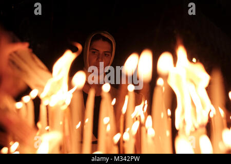 An Orthodox Christian pilgrim lights candles as she prays inside the Church of Holy Sepulchre in the Christian Quarter old city East Jerusalem Israel Stock Photo