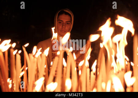 An Orthodox Christian pilgrim lights candles as she prays inside the Church of Holy Sepulchre in the Christian Quarter old city East Jerusalem Israel Stock Photo