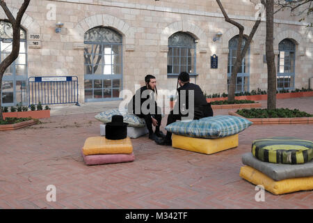 Two young Orthodox Jews chatting at the sculpted pillow area by designer Smadar Carmeli at the courtyard of the Jerusalem city hall in Safra Square West Jerusalem, Israel Stock Photo
