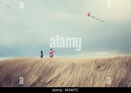 Man and woman standing in a field flying a kite Stock Photo