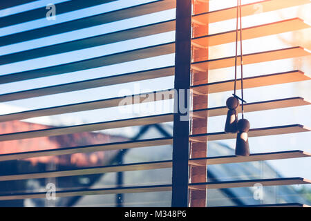 Close up open sunshade or curtain with ray of sunlight through from the window in vintage style. Stock Photo