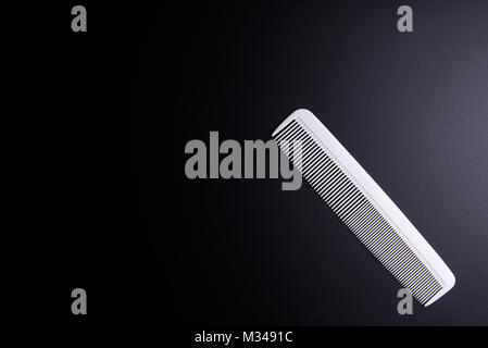 White Comb Barber on black background. Hairdresser salon concept, Hairdressing Set. Haircut accessories. Copy space image, flat lay Stock Photo
