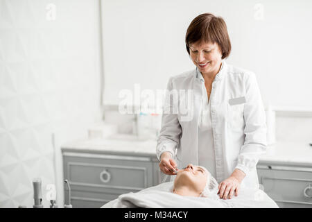 Senior woman cosmetologist making facial procedure to a young client in a luxury medical resort office Stock Photo