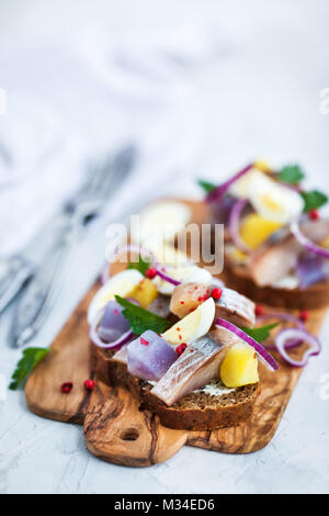 Open sandwich (smorrebrod) with herring, onion, potato and eggs Stock Photo