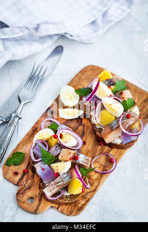 Open sandwich (smorrebrod) with herring, onion, potato and eggs Stock Photo