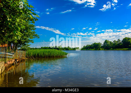 Wide angle lake landscape with trees, forest and clouds in the background Stock Photo