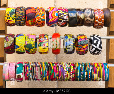 Close up of multiple colorful, fabric covered bangle bracelets on a rack. Photographed in natural light at eye level. Stock Photo