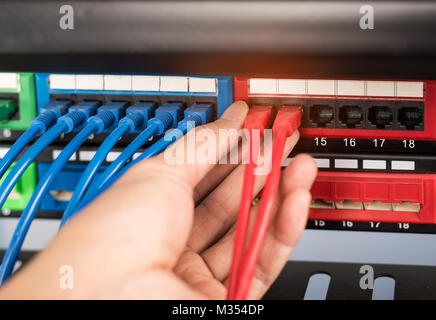 administrator holding network cables connected to servers Stock Photo