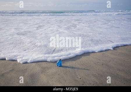 Single use plastic bottle washed up on beach Stock Photo