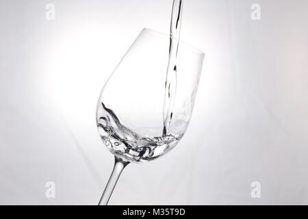 Water splashing as it falls in empty wine glass Stock Photo