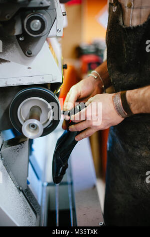 shoemaker adjusts and repairs shoe sole in his workshop close-up of hands at work Stock Photo