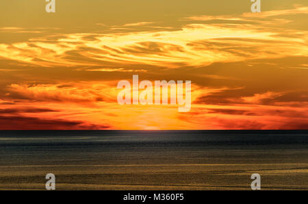Stylized abstract landscape seascape sunset long exposure with clouds under different shades of blue, orange, yellow and red. Stock Photo