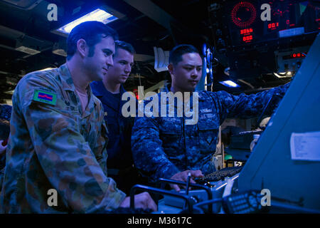 150728-N-UN259-045 DARWIN, Australia (July 28, 2015) Operations Specialist 2nd Class Kevin Paras, from San Francisco, Calif. demonstrates how to use a radar to a U.S. Navy Midshipmen and an Australian navy sailor during a surface contact drill in the combat information center of the Arleigh Burke-class guided-missile destroyer USS Preble (DDG 88). Preble is deployed to the 7th Fleet area of operations in support of security and stability in the Indo-Asia-Pacific region. (U.S. Navy photo by Mass Communication Specialist Seaman Alonzo M. Archer/Released) US and Australian Sailors Conduct a Surfa Stock Photo