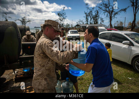 U.S. Marines with Combat Logistics Battalion 31, 31st  Marine Expeditionary Unit, distribute water to local civilians during typhoon relief efforts in Saipan, Aug. 11,  2015. The 31st MEU and the ships of the Bonhomme Richard Amphibious Ready Group are assisting the Federal Emergency Management Agency with distributing emergency relief supplies to Saipan after the island was struck by Typhoon Soudelor Aug. 2-3. (U.S. Marine Corps photo by GySgt Ismael Pena/Released) Marines Distribute Water to Local Civilians during Typhoon Relief Efforts in Saipan by #PACOM Stock Photo