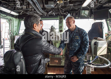 170118-N-TH560-118 SASEBO, Japan (Jan. 18, 2017) Capt. Jeffrey Ward (right), commanding officer of amphibious assault ship USS Bonhomme Richard (LHD 6), welcomes Sunao Gushiken (left), journalist for Japanese newspaper The Asahi Shimbun, on the bridge of Bonhomme Richard during a shipÕs tour. Bonhomme Richard, forward-deployed to Sasebo, Japan, is serving forward to provide a rapid-response capability in the event of a regional contingency or natural disaster. (U.S. Navy photo by Mass Communication Specialist 3rd Class Jeanette Mullinax/Released) USS Bonhomme Richard's CO welcomes media aboard Stock Photo