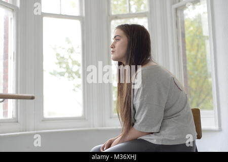 A teenage girl with long hair is alone in a bright room Stock Photo