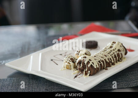 Delicious chocolate black and white cake on white rectangular plate on table Stock Photo