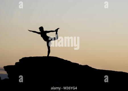 female doing yoga at sunrise at Horseshoe Bend on a rock Stock Photo