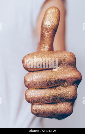 Golden female hand showing thumb up on white background close-up, vertical framing Stock Photo