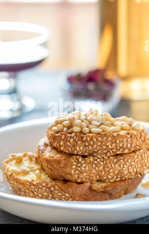 Toasts of bread with sesame seeds homemade cake in stack decorated with pine nut on white plate Stock Photo
