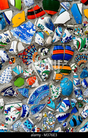 colorful broken tiles in different shapes and sizes on a plastered wall background Stock Photo