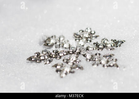 Glittery snowflake ornament in fresh powdery snow on a sunny day. Stock Photo