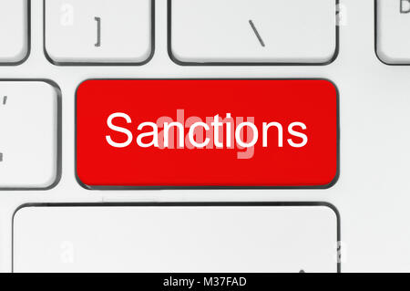 Red button with sanctions word on the keyboard close-up Stock Photo