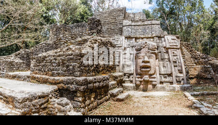 Old ancient stone Mayan pre-columbian civilization pyramid with carved face and ornament hidden in the forest, Lamanai archeological site, Orange Walk