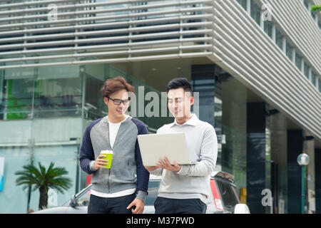 Two smiling young businessmen walking and talking in the city Stock Photo