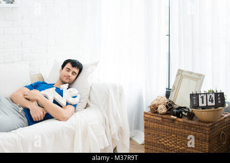 Young handsome man slepping and hugging LOVE alphabet in sofa in bedroom at home. Young single man want someone to love. Stock Photo