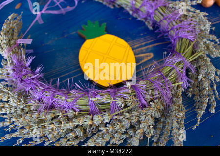 Wreath of lavender and yellow pineapple on blue wooden board Stock Photo