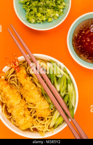 Japanese Style Tiger Prawn Tempura Noodle Soup With Spring Onions Against An Orange Background