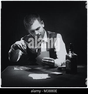 Tough guy playing his cards close to his chest at the poker table Stock Photo