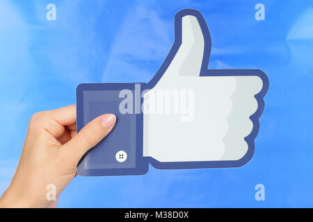 Kiev, Ukraine - September 4, 2017: Hand holds Facebook logo printed on paper on blue paper background. Facebook is a well-known social networking serv Stock Photo