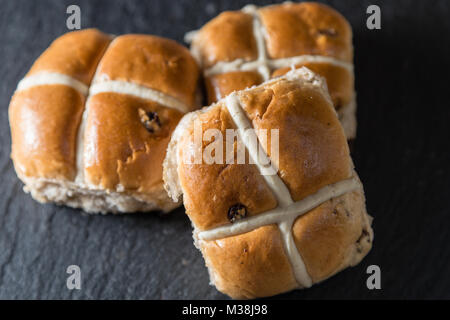 Three hot cross buns on a drak grey plate.  These are traditional Easter food Stock Photo