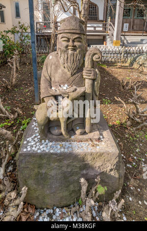 Kamakura, Japan - November 22, 2017 : Coins around statue of Jurojin (God of longevity) one of the Seven Gods of Fortune 'Shichifukujin', Myoryuji Bud Stock Photo