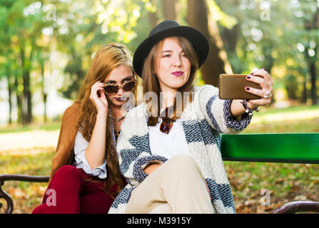 Girlfriends taking a selfie on a bench in the park Stock Photo