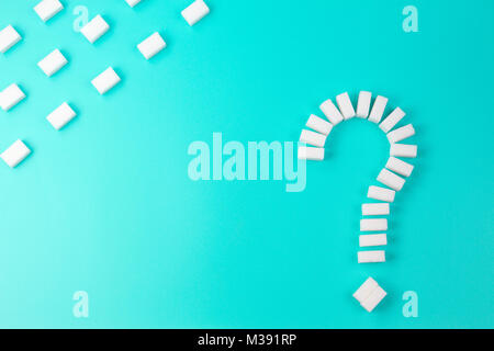 Sugar cubes shaped as a question mark sign on turquoise background. Stock Photo