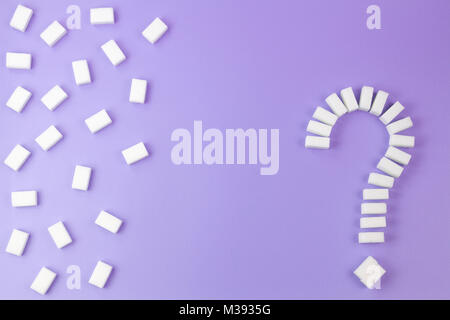 Sugar cubes shaped as a question mark sign on violet background. Stock Photo