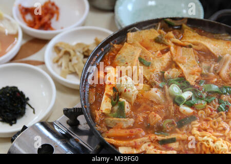 Close up of Korean Army Stew (Budae Jjigae) hot pot with the side dishes at Korean restaurant, Busan, South Korea Stock Photo