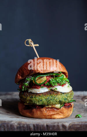 Vegetarian burger made of green pea, butter beans and spinach  with sundried tomato pesto and grilled courgette Stock Photo