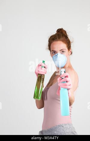 MODEL RELEASED. Woman wearing face mask and gloves holding cleaning materials in her hands. Stock Photo