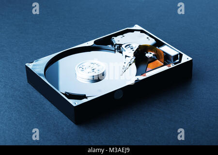 Open disassembled hard disk on black plastic background. Blue Toned Image Stock Photo