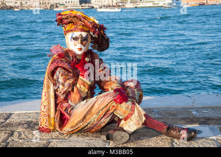 Venice, Veneto, Italy, 10th February 2018. Colourful costumes at the Venice Carnival on a sunny day on the last weekend of the festival. People posing on San Giorgio Maggiore Island at sunset. Stock Photo